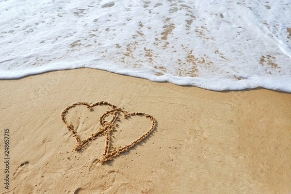 Fototapeta Valentine's day concept, two heart shape drawing on sand beach with ocean background.