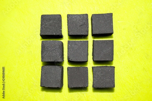 Obraz coconut coal cubes on bright green background