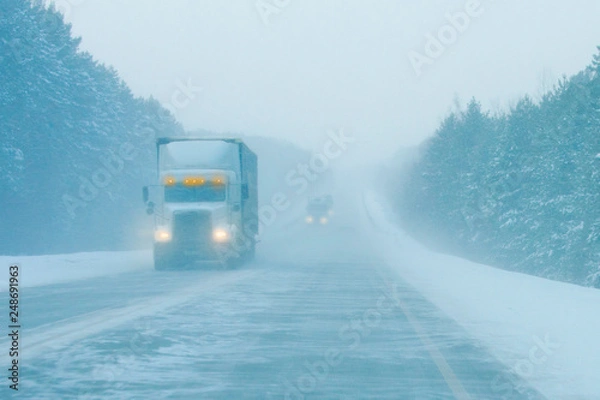 Fototapeta trucks on the road in a snow storm