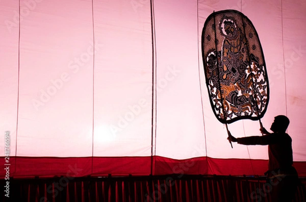 Fototapeta A man is playing an old Thai traditional shadow play called as Nang Yai,Composed to Violet tone.