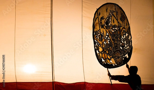 Fototapeta A man is playing an old Thai traditional shadow play called as Nang Yai,Composed to Golden tone.