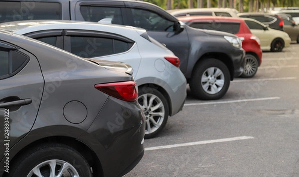 Fototapeta Closeup of back or rear side of brown car and other cars parking in parking area in twilight evening. 