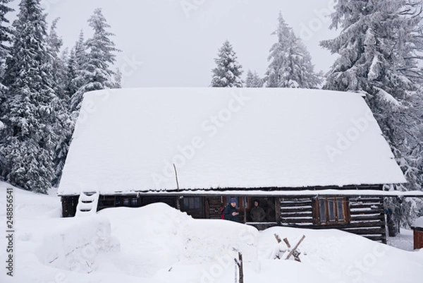 Obraz Couple standing on the porch of a snow covered chalet 