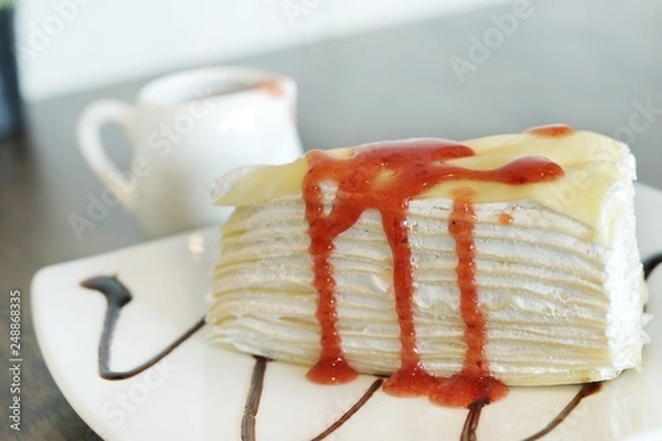 Fototapeta Close up, A Piece of crape cake with strawberry sauce on white ceramic plate for serving