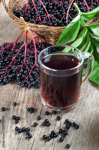 Fototapeta Clusters of ripe elderberry and drink in a glass