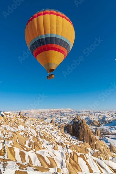 Obraz colorful balloon over the extraordinary rocks formations rock hills on snowy winter of Cappadocia, Nevsehir,