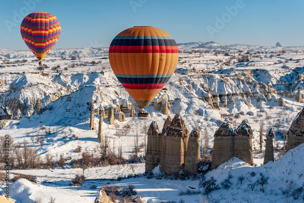 Fototapeta colorful balloon over the extraordinary rocks formations rock hills on snowy winter of Cappadocia, Nevsehir,