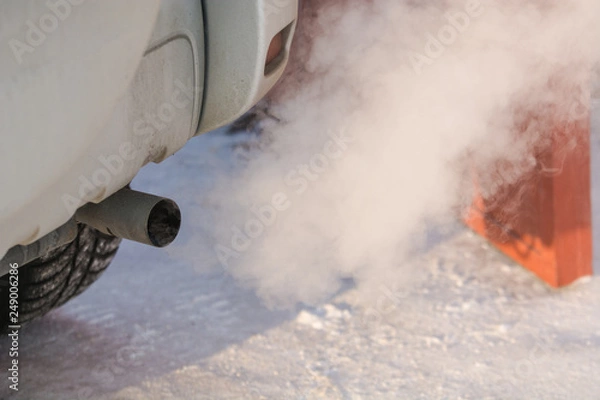 Fototapeta The car smokes in the winter. Smoke from a car pipe. The car is buzzing in the cold.