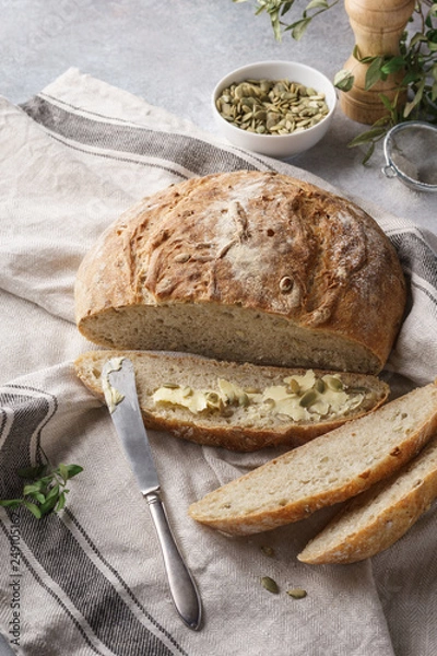 Fototapeta Whole grain bread and slice with pumpkin seeds and butter.