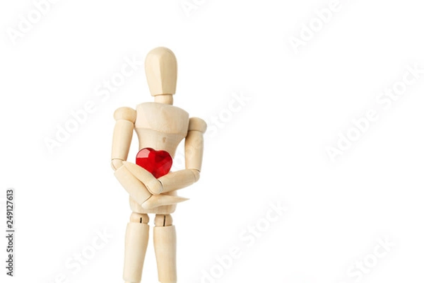 Fototapeta The wooden figure of a man holds in his hands a red heart on a white background. Gives the heart