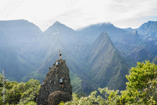 Fototapeta Three adventurous hikers climbing a rocky pinnacle in the junle of Reunion Island