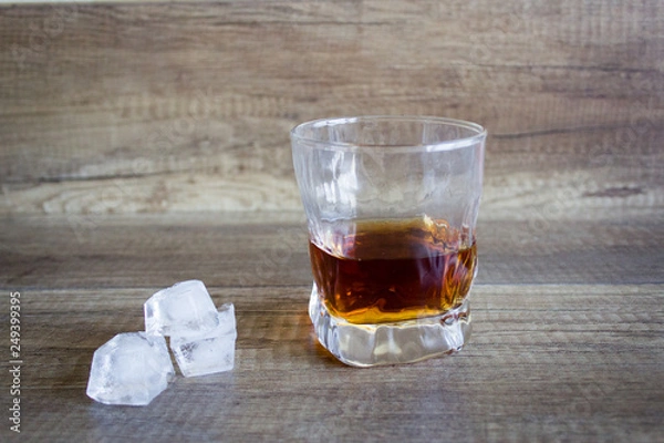Fototapeta Bourbon Whiskey in a glass with ice on wooden table background
