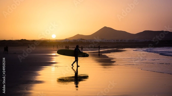 Fototapeta Silhouette of a Surfer on Famara beach at sunset