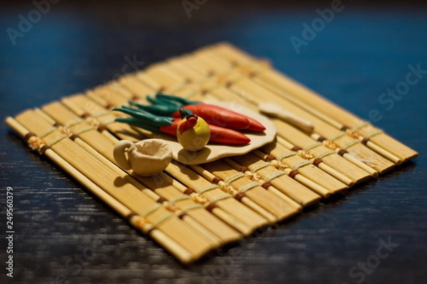 Fototapeta Plasticine crafts on a bamboo mat. Carrots, apple with a worm, a plate, circling and a spoon.