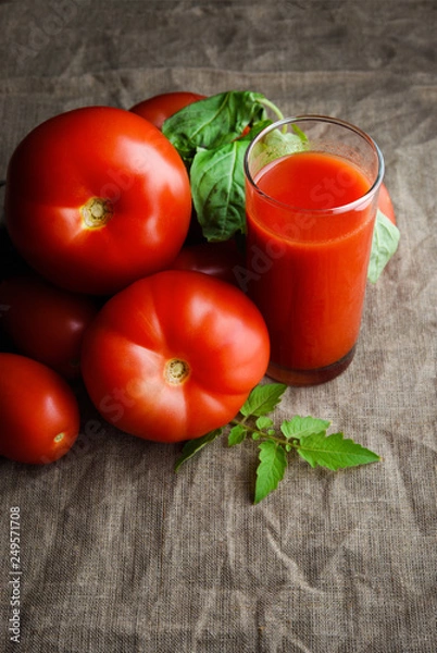 Fototapeta Glass of fresh tomato juice and tomatoes around on cloth background