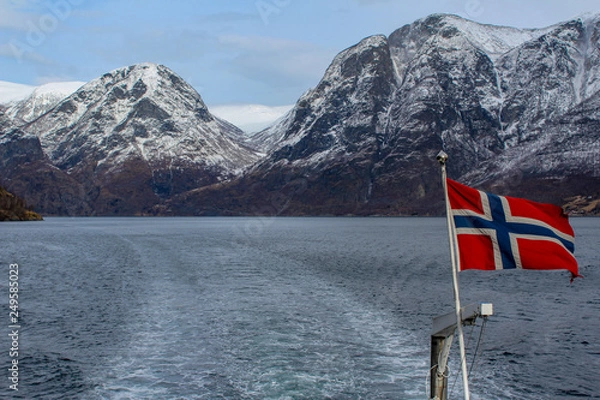 Fototapeta Norwegian flag in the wind during a cruise on the naeroyfjord, Norway