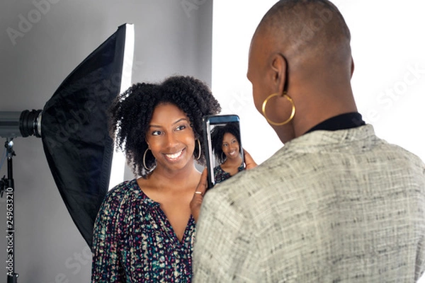 Fototapeta Black female actress doing a self tape audition via cell phone camera in a studio while reading to a casting director.  Depicts the Hollywood entertainment industry process.