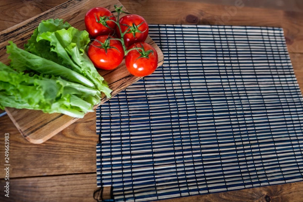 Fototapeta Flat lay. Kitchen table with lettuce and red tomatoes. Copy space