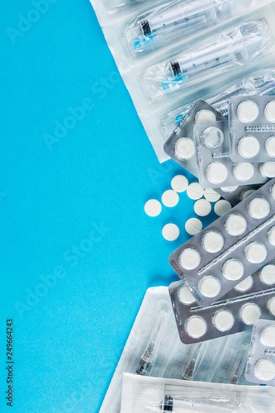 Fototapeta packs of white pills and syringes on a blue background