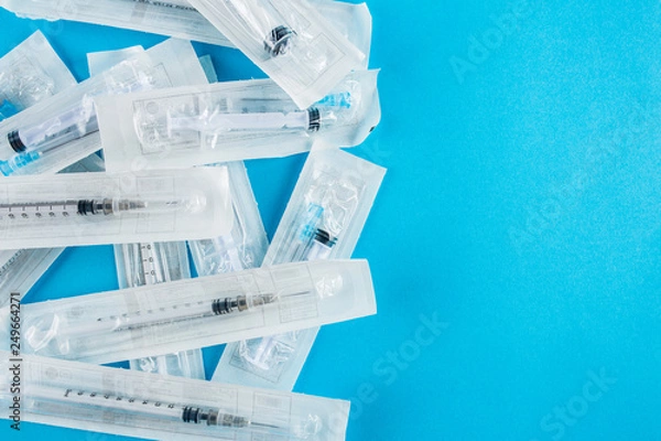 Fototapeta Large packages with cocaine on a blue background, medical syringe close