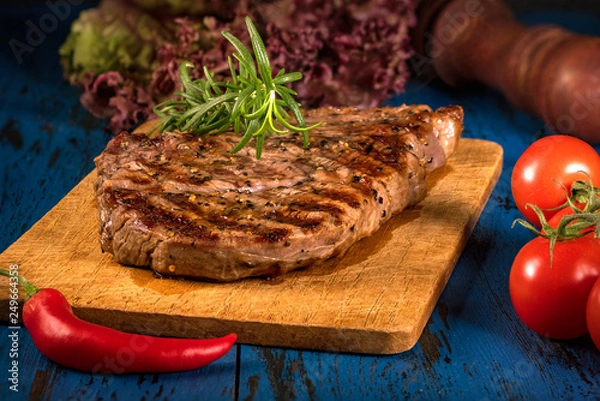Obraz Grilled steak with spices on a dark blue wooden table