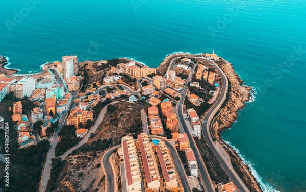 Fototapeta Beautiful mediterranian coastline near Valencia, Spain with small town, hotels, buildings and roads. Autumn winter blue turquoise cold sea water and warm colors coastline. Aerial drone shot view