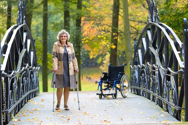 Obraz older woman practicing walking on crutches