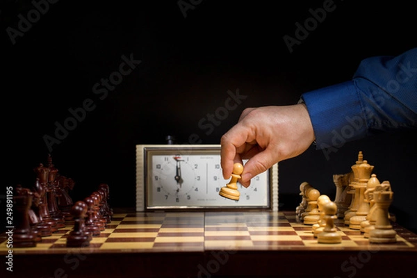 Obraz Detail of chess competition. Mans hand making the first move in a chess game, moving the pawn one field forward. Selective focus