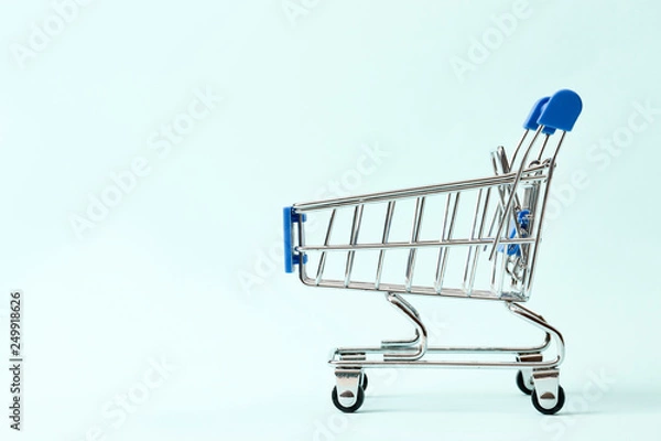 Fototapeta Discounts concept. Shopping cart  on a blue background with space for text