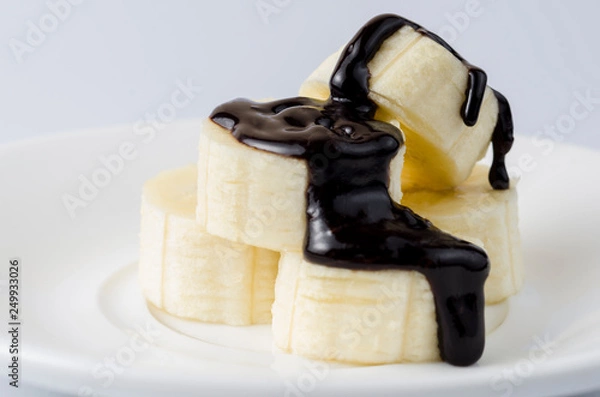 Obraz Sliced ​​bananas in chocolate icing on a light background