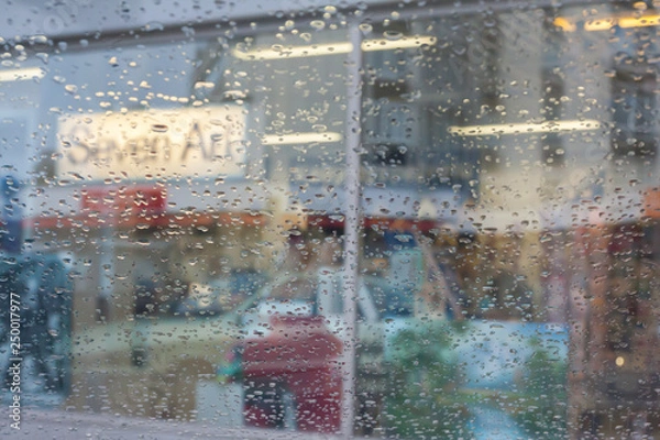 Fototapeta Rain drops on car glass, focus on raindrops. View to the street.