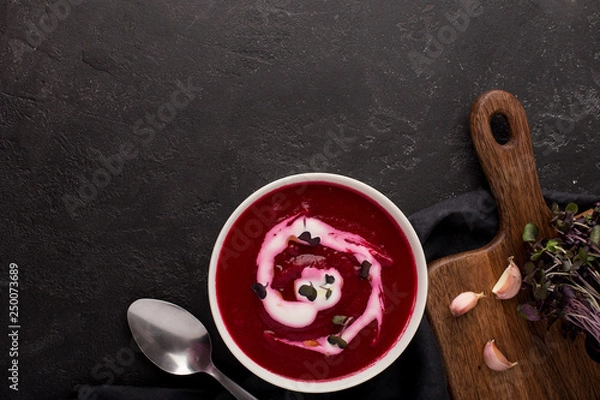 Fototapeta two plates with beetroot soup and sour cream on black background