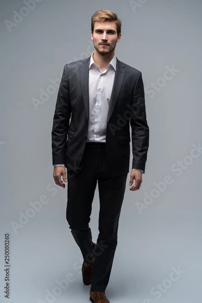 Fototapeta Perfect suit. Full length of handsome young man in suit looking at camera while standing against gray background