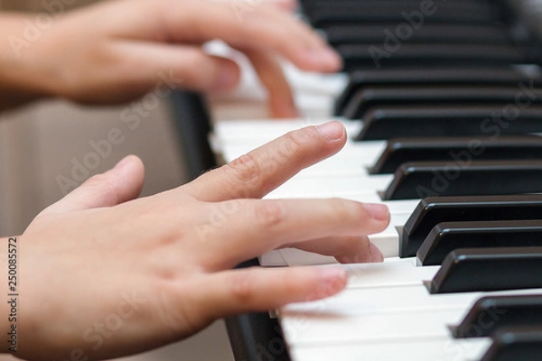 Fototapeta Hands of the child on the piano keys. Selective focus.