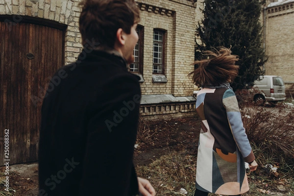 Fototapeta stylish couple having fun and laughing in autumn park. man and woman running and playing, joyful moments of true happiness. family togetherness concept.  atmospheric