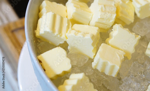 Fototapeta Cubes of fresh butter placing on ice in white bowl. Hotel restaurant breakfast buffet