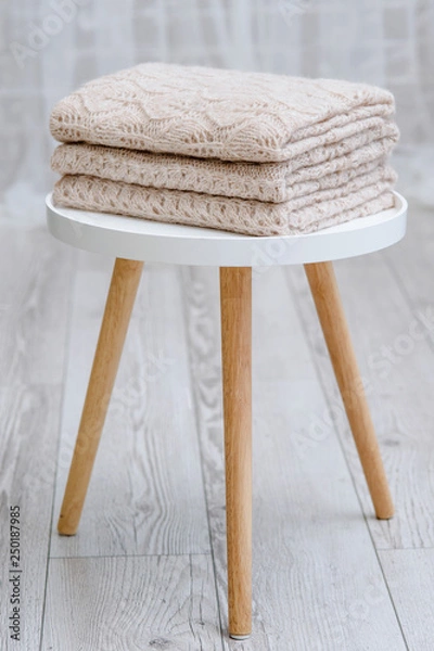 Obraz A stack of knitted handmade plaids is lying on a tabouret