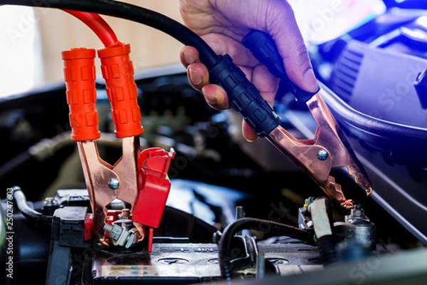 Obraz selective focus charging car with electricity trough cables.