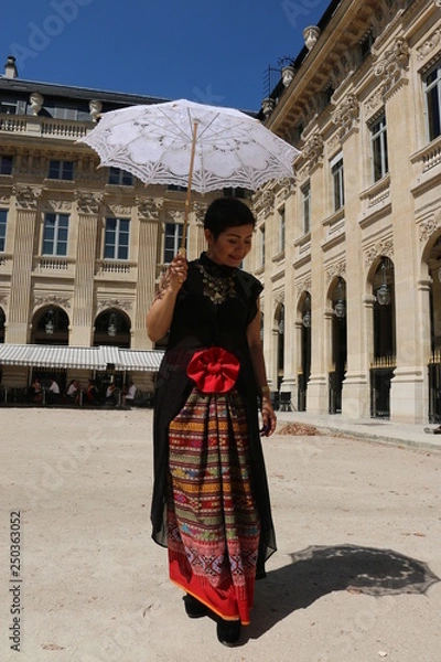 Fototapeta Femme avec ombrelle blanche marchant dans la cour du palais royal à Paris