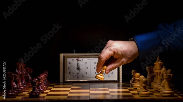 Fototapeta Detail of chess competition. Mans hand making the first move in a chess game, moving the pawn one field forward. Selective focus