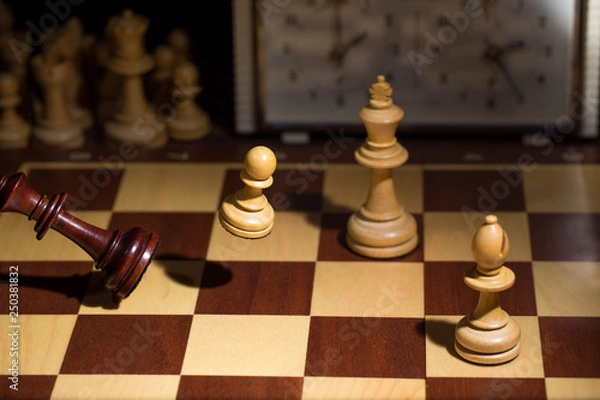 Obraz White's victory on the chessboard. The king fell.Strategy, victory, intelligence.The pawn attacks the king. Shot in motion. Flying figures.
