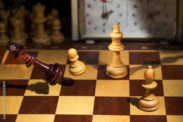 Obraz White's victory on the chessboard. The king fell.Strategy, victory, intelligence.The pawn attacks the king. Shot in motion. Flying figures.