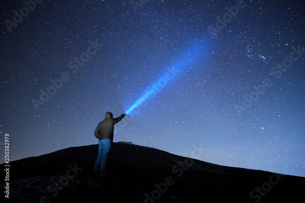 Obraz Man Pointing Blue Flashlight To Starry Sky
