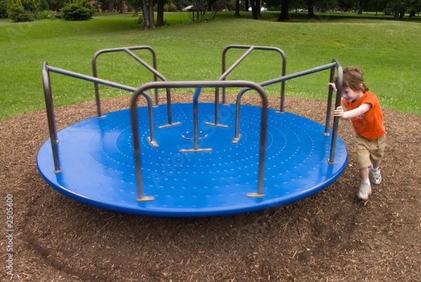 Obraz young boy pushes a merry-go-round