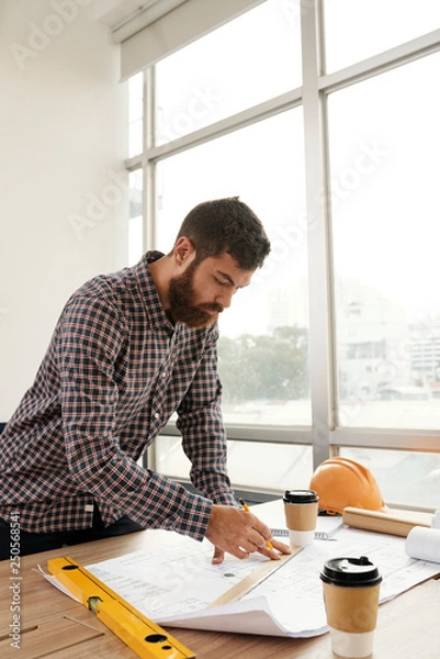 Fototapeta Engineer double checking blueprint