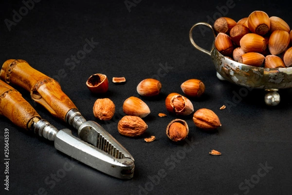 Obraz huzelnuts in silver bowl on a table and nutcracker
