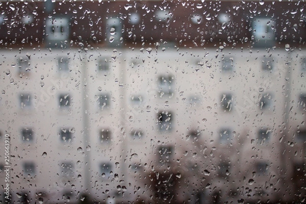 Fototapeta Drops of rain on glass , rain drops on clear window. Water condensation on transparent glass over city landscape or building in blur.