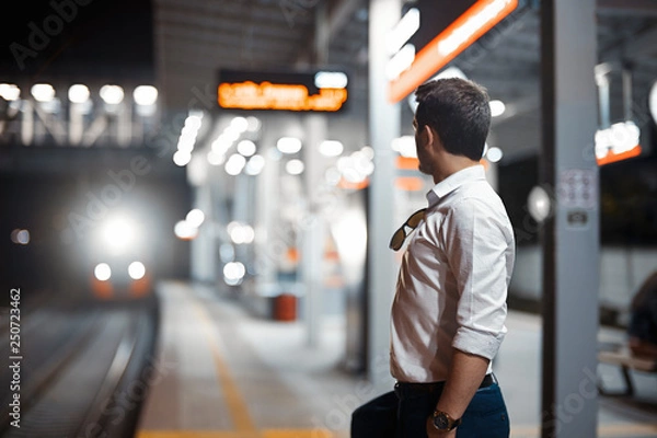 Obraz Young attractive businessman waiting for train in metro or subway.
