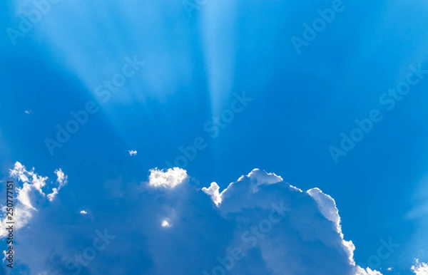 Obraz Blue sky and white clouds blue sky on a bright day with white clouds coming in floating come to cover sun causes a white beam causing beauty in the sky.