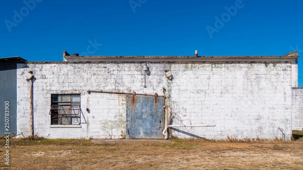 Fototapeta Old building textured surface with rusty steel door and window